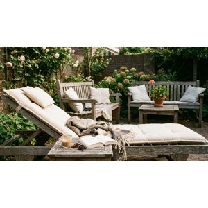 Gezellige tuin met ligstoel en houten meubels