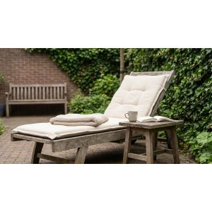 Houten ligstoel met kussen in groene tuin