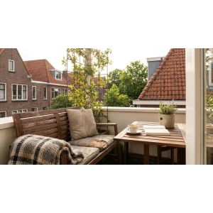 Gezellig balkon met houten bank en koffie