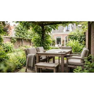 Houten tuintafel onder pergola in groene stadstuin