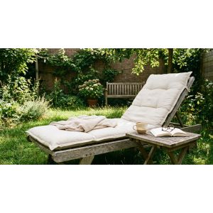 Houten ligstoel met kussens in groene tuin