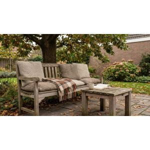 Houten tuinbank met kussens en plaid in herfsttuin