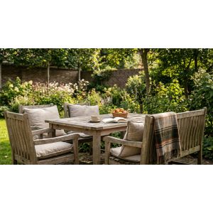 Houten tuintafel met stoelen in weelderige zonnige tuin